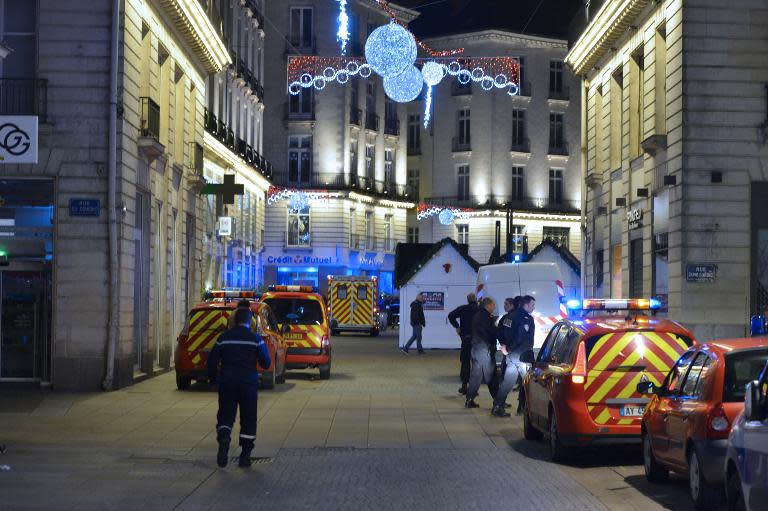 Police stand on the site where the driver of a van ploughed into a Christmas market, injuring at least 10 people, before stabbing himself, in Nantes on December 22, 2014