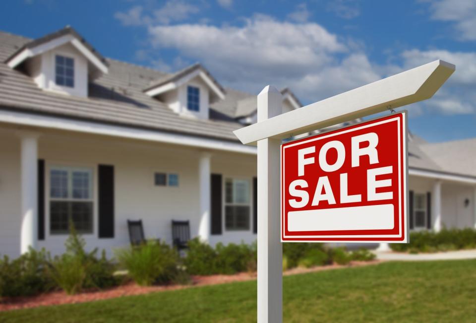 A house with a "for sale" sign in front of it.