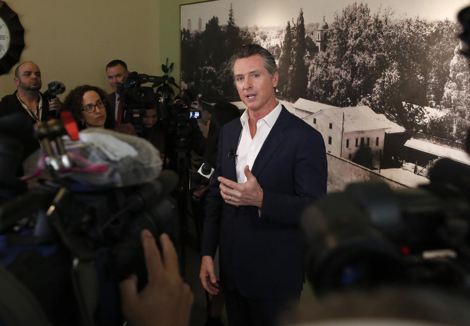 In this photo taken Tuesday, March 26, 2019, Gov. Gavin Newsom talks with reporters in Sacramento, Calif. Newsom, on Thursday, March 28, says PG&E plans to remake its board of directors with hedge fund financiers and people who have little experience in utility operations and safety. Putting hedge fund managers in charge of the company, said Newsom, will send a message the utility prioritizes profits over providing safe and reliable energy service. The utility did not immediately comment. (AP Photo/Rich Pedroncelli)