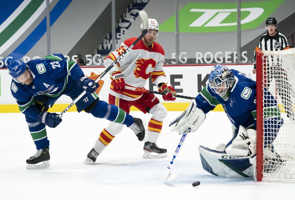 Vancouver Canucks defenseman Alexander Edler (23) tries to stop Calgary Flames center Sam Bennett (93) from getting a shot on Canucks goaltender Thatcher Demko (35) during the first period of an NHL hockey game Thursday, Feb. 11, 2021, in Vancouver, British Columbia. (Jonathan Hayward/The Canadian Press via AP)