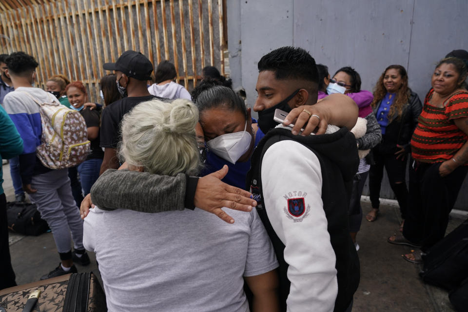 FILE - In this July 5, 2021, file photo, Alex Cortillo, right, of Honduras gets a hug from Erika Valladares Ponce, of Honduras, center, and others, as he waits to cross into the United States to begin the asylum process in Tijuana, Mexico. Two nongovernmental organizations said Friday, July 30, 2021, that they are ending cooperation with the Biden Administration to identify the most vulnerable migrants waiting in Mexico to be admitted to the United States to seek asylum. (AP Photo/Gregory Bull, File)