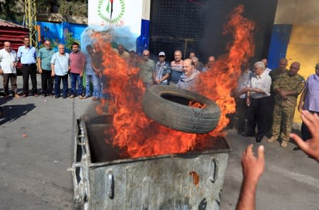 A demonstrator throws a tire into a burning garbage bin during a protest against Bahrain's conference about U.S. President Donald Trump's vision for Mideast peace plan, in Ain al-Hilweh Palestinian refugee camp, near Sidon