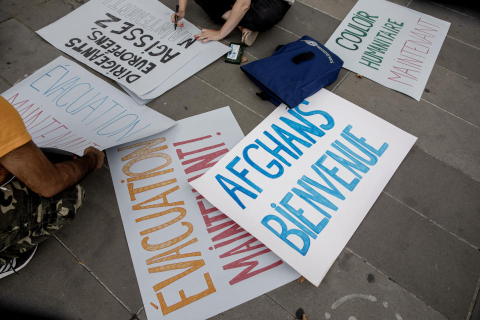 A woman prepares posters saying "Afghans welcome", "evacuation now" and "European rulers, act now" during a demonstration in Paris, Sunday, Aug. 22, 2021. Afghan associations in France have called on people to gather at the Republic Plaza in Paris on Sunday to show their solidarity toward evacuees and refugees from Afghanistan, after the Taliban took power in the country, and France has evacuated some hundreds of people from Kabul who worked with the French government or French groups in Afghanistan. (AP Photo/Adrienne Surprenant)