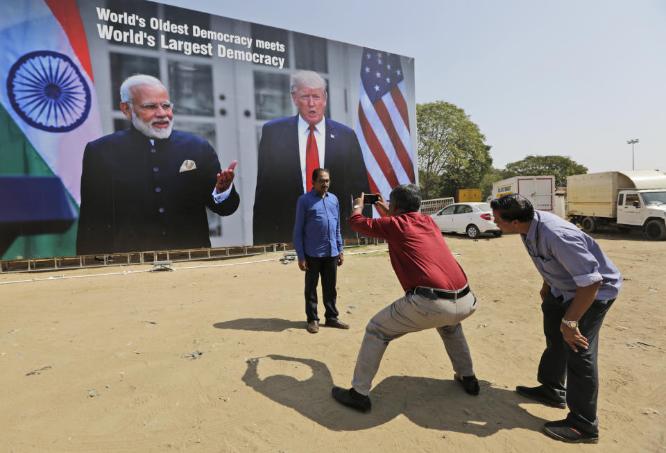 A man stands for a photograph in front of a hoarding welcoming U.S President Donald Trump, at the airport ahead of his visit in Ahmedabad, India, Saturday, Feb. 22, 2020. To welcome Trump, who last year likened Modi to Elvis Presley for his crowd-pulling power at a joint rally the two leaders held in Houston, the Gujarat government has spent almost $14 million on ads blanketing the city that show them holding up their hands, flanked by the Indian and U.S. flags. (AP Photo/Ajit Solanki)