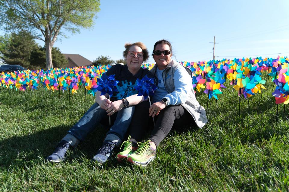Penny Harvey, executive director of Tralee Crisis Center, and Shelly Bohannon sit Saturday in front of 1,023 pinwheels, each representing a child who received services from The Bridge Children's Advocacy Center in Amarillo.