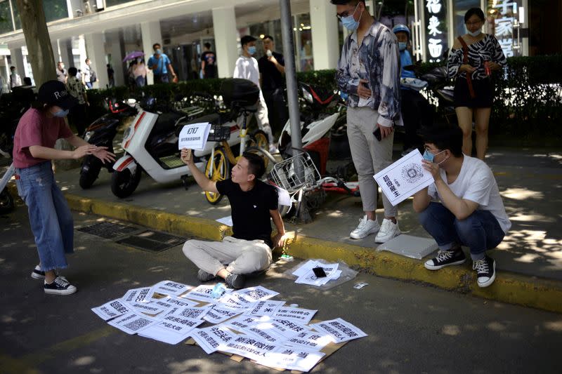 Employees of a recruitment platform promote their company at a stall they set up by a street, near an office complex in Beijing's business district