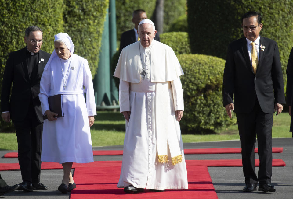 Pope Francis, center, walks with his cousin Ana Rosa Sivori, left, and Thailand's Prime Minister Prayuth Chan-ocha, right, during a welcoming ceremony at the government house in Bangkok, Thailand, Thursday, Nov. 21, 2019. Pope Francis is on a four-day visit to Thailand. (AP Photo/Sakchai Lalit)