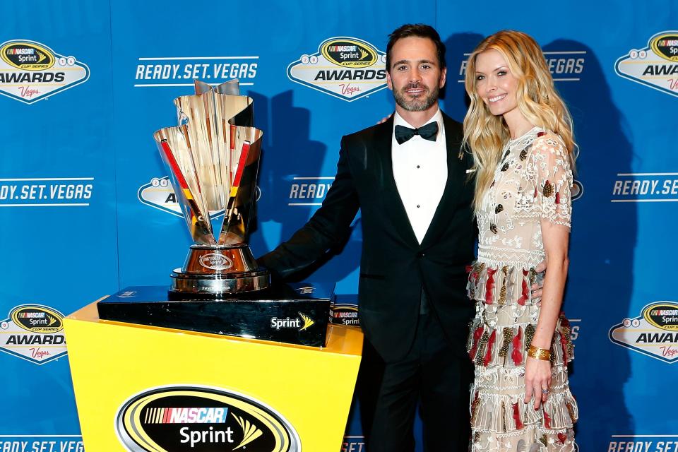 Jimmie Johnson y su esposa Chandra de pie con el trofeo del campeonato luego de su séptimo y último título de la Serie de la Copa en el banquete de los Premios NASCAR 2016.