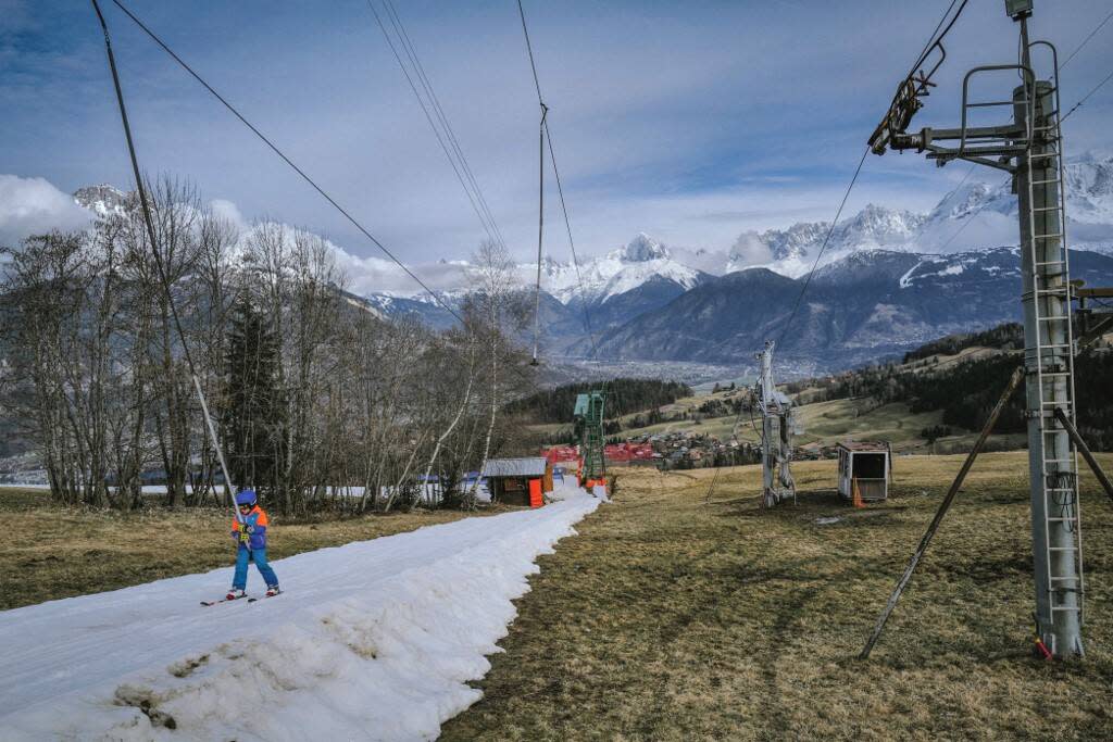 Un skieur fait du téléski sur une piste sans neige à la station de ski de Cordon près de Megève, avec le Mont Blanc en arrière-plan en France le 12 février 2024.