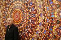 British artist Damien Hirst stands beside the 2006 piece "I Am Become Death, Shatterer of Worlds", butterflies and household gloss on canvas, during a media preview of the first substantial survey show of his work in the UK at the Tate Modern gallery in London, Monday, April 2, 2012. The exhibition, timed for the culmination of the Cultural Olympiad and due to open to the public on Wednesday, showcases over 70 of Hirst's works since he first came to public attention in 1988. (AP Photo/Matt Dunham)