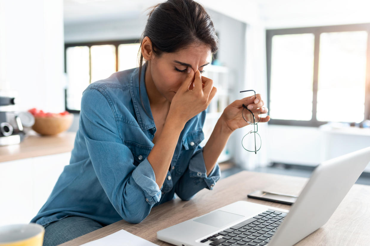 A woman looking stressed at her laptop