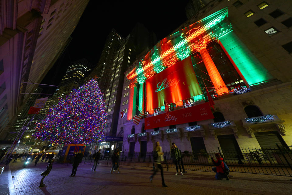 Pedestrians walk past a Christmas tree on Broad Street and the seasonal lights illuminating the New York Stock Exchange. (Photo: Gordon Donovan/Yahoo News)