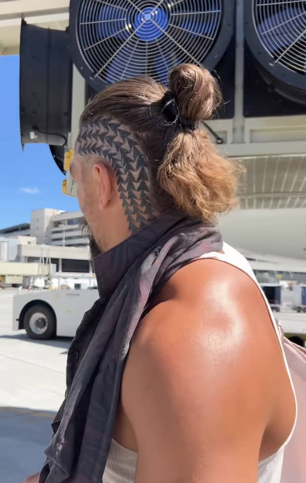 The tattoo features three columns of arrows on the side of his head running from the base of his neck's, around his ear, to the top of his scalp