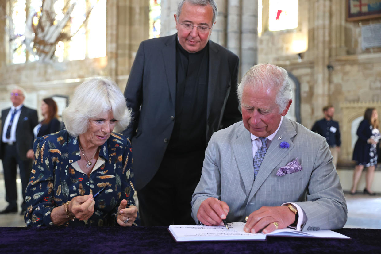 EXETER, UNITED KINGDOM - JULY 19: Camilla, Duchess of Cornwall  and Prince Charles, Prince of Wales sign the visitors book during a visit to Exeter Cathedral on July 19, 2021 in Exeter, United Kingdom. Founded in 1050, The Cathedral continues to offer daily Christian worship and choral music, alongside its roles as a community hub, heritage destination and venue for concerts and events. It is home to an extensive library and archive, housing important treasures such as the Exeter Book – thought to be the world’s oldest surviving book of English literature. The visit celebrates the city’s designation as a UNESCO City of Literature and launch of The Royal College of Nursing’s Prince of Wales Nursing Cadet Scheme in England.  (Photo by Chris Jackson - WPA Pool/Getty Images)