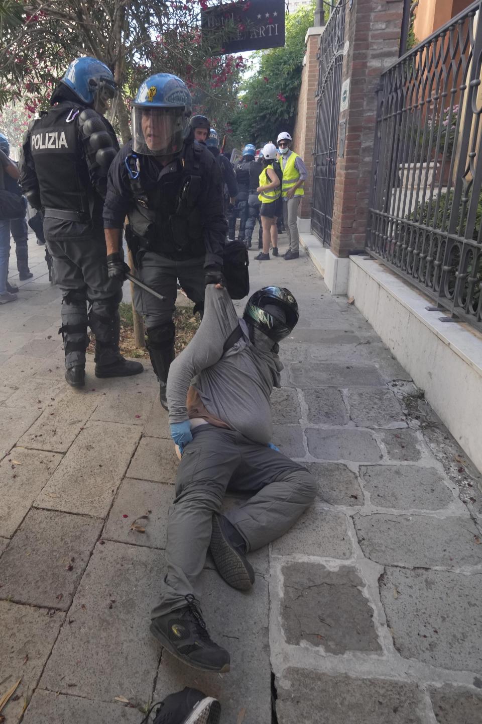 A demonstrator is blocked by an Italian policemen during clashes broke out between demonstrators and Italian Policemen in riot gears on the occasion of a protest against the G20 Economy and Finance ministers and Central bank governors' meeting in Venice, Italy, Saturday, July 10, 2021. (AP Photo/Luca Bruno)