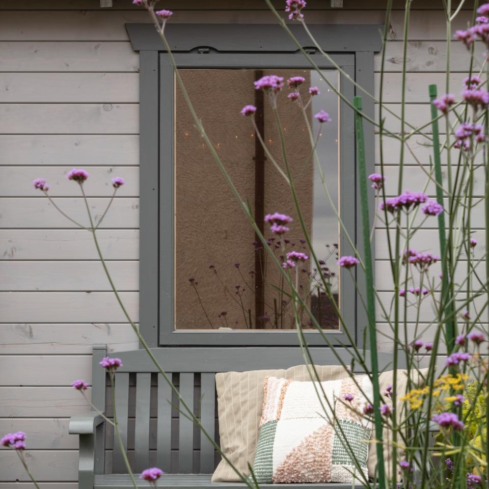 A window from the outside with a bench underneath