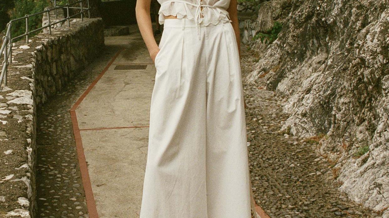 a model wearing white wide leg palazzo pants by doen in a roundup of the best summer pants for women 2024