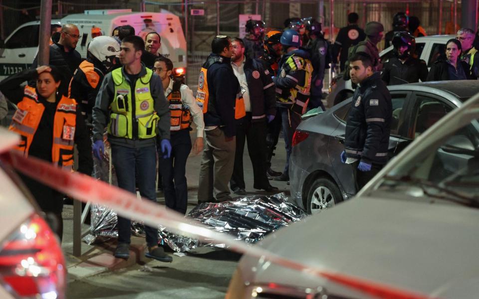 Israeli emergency service personnel and security forces stand near a covered body at the site of a reported attack - AHMAD GHARABLI