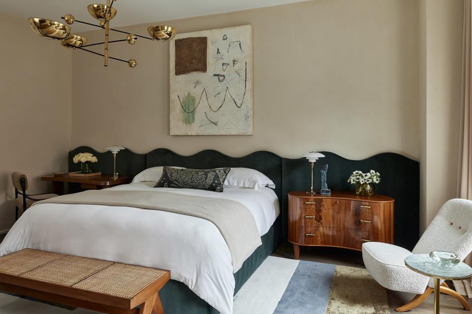This primary bedroom in an 1889 row house in Chicago’s Lincoln Park neighborhood designed by Wendy Labrum features a custom scalloped headboard that runs the length of the room and an original painting by artist Colt Seager.