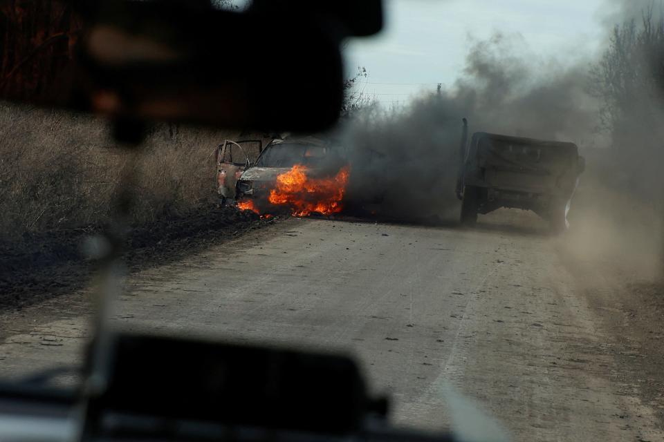 Ukrainian servicemen move past a burning car hit by a kamikaze drone outside the front line town of Avdiivka on Wednesday (REUTERS)