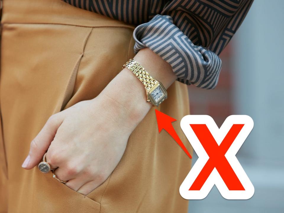 red x and arrow pointing at a simple gold watch on someone's wrist