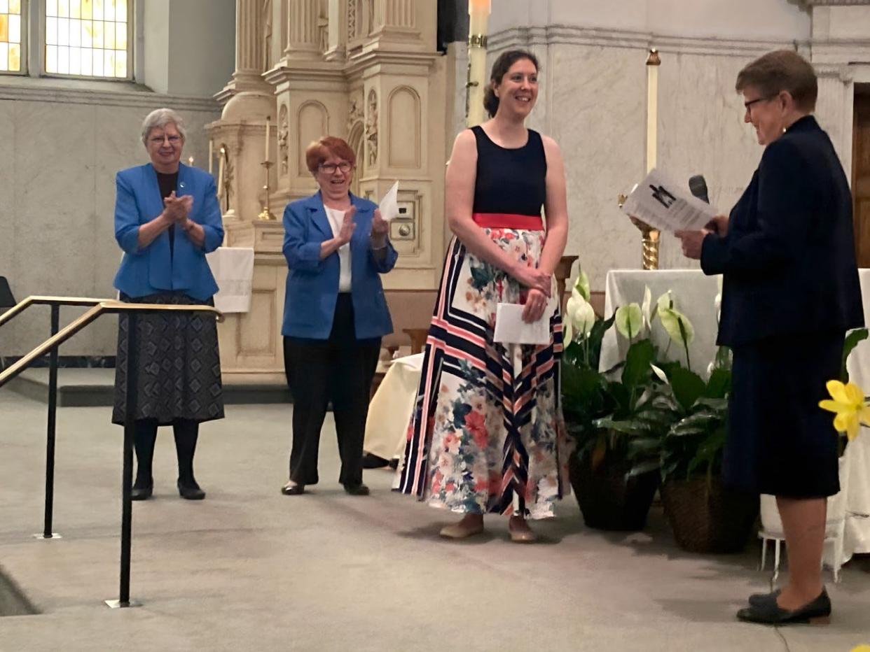 Audra Turnbull (center, standing) is shown with Sister Mary Jane Herb, IHM president (right) as others congratulate her on professing final vows with the IHM Sisters.