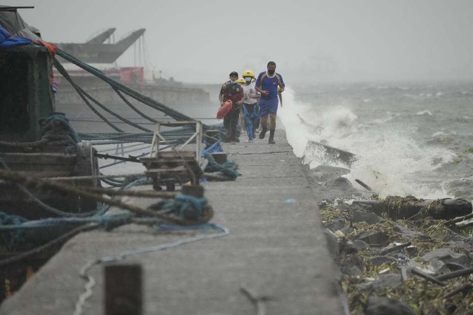 Rescuers run as they check residents living at the seaside slum district of Tondo while Typhoon Noru approaches Manila, Philippines, Sunday, Sept. 25, 2022. The powerful typhoon shifted and abruptly gained strength in an "explosive intensification" Sunday as it blew closer to the northeastern Philippines, prompting evacuations from high-risk villages and even the capital, which could be sideswiped by the storm, officials said. (AP Photo/Aaron Favila)