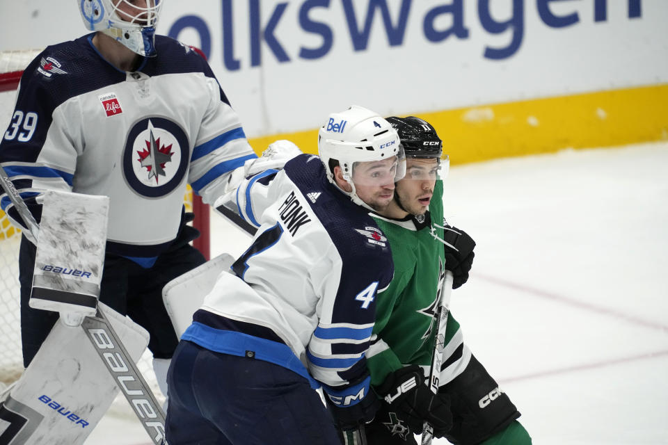 Winnipeg Jets defenseman Neal Pionk (4) and Dallas Stars' Logan Stankoven, right, compete in front of the net during the first period of an NHL hockey game in Dallas, Thursday, April 11, 2024. (AP Photo/Tony Gutierrez)