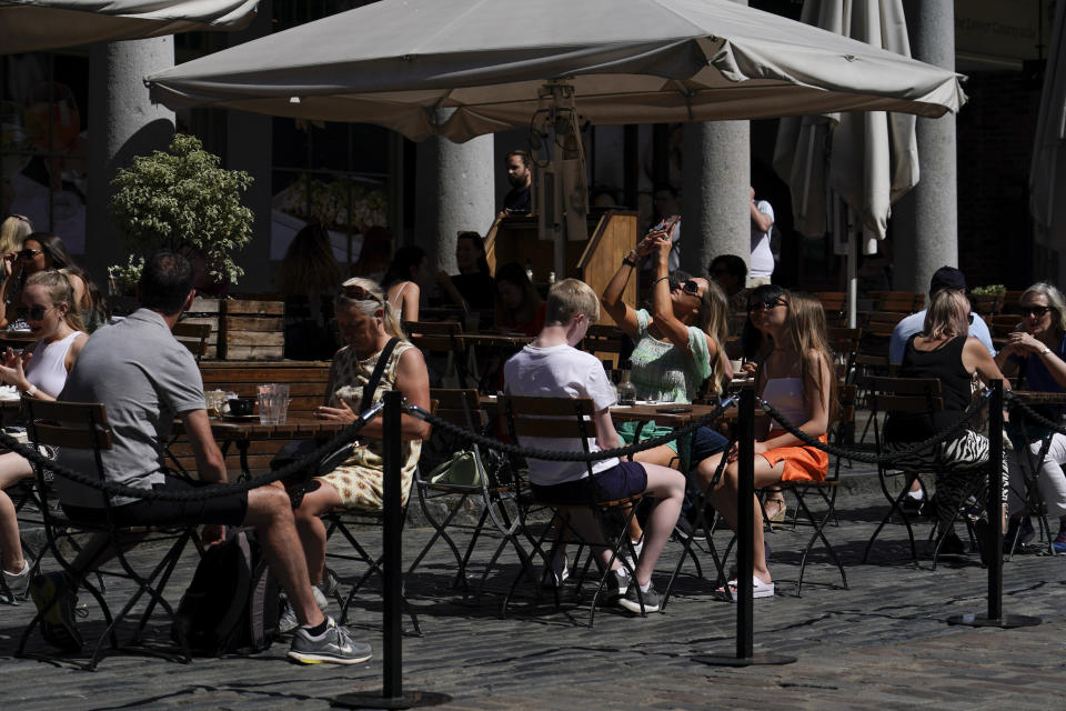 People sit at outside tables in Covent Garden, London, Monday, June 14, 2021. British Prime Minister Boris Johnson is expected to confirm Monday that the next planned relaxation of coronavirus restrictions in England will be delayed as a result of the spread of the delta variant first identified in India. (AP Photo/Alberto Pezzali)