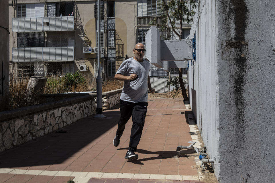 An Israeli runs for cover in Ashdod, Israel during sirens warning of incoming rockets fired from Gaza Strip, Tuesday, May 18, 2021. (AP Photo/Heidi Levine)