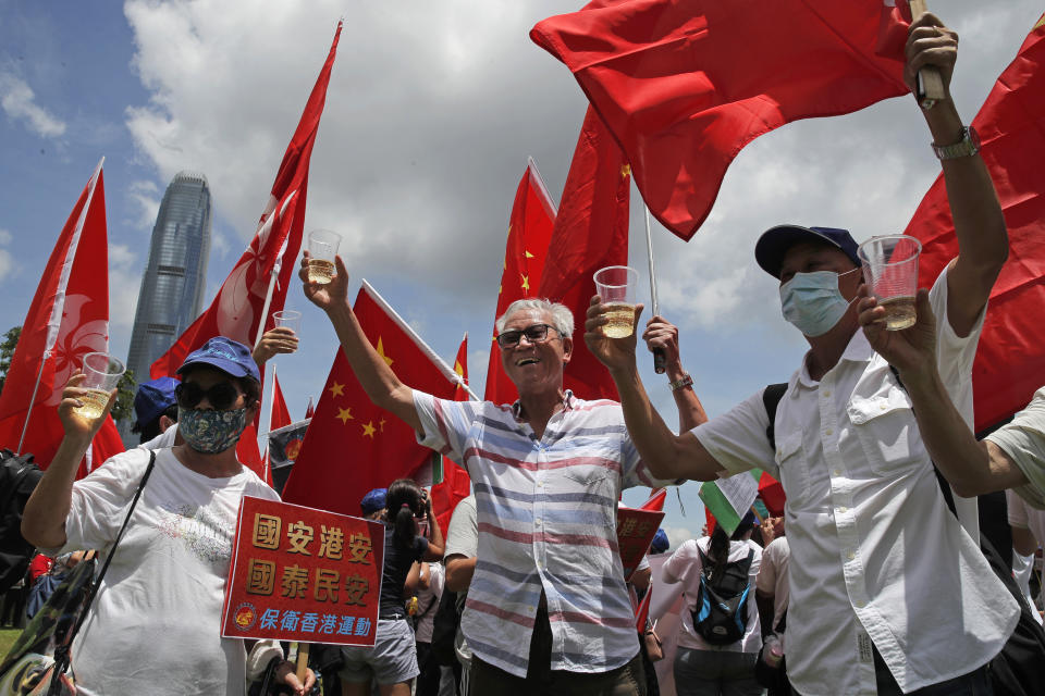 Pro-China supporters holding Chinese national flags, toast during a rally to celebrate the approval of a national security law for Hong Kong, in Hong Kong, Tuesday, June 30, 2020. Hong Kong media are reporting that China has approved a contentious law that would allow authorities to crack down on subversive and secessionist activity in Hong Kong, sparking fears that it would be used to curb opposition voices in the semi-autonomous territory. A placard reads "Country secure, Hong Kong secure, the country prospects, the people at peace". (AP Photo/Kin Cheung)