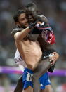 Gold medalist Ezekiel Kemboi of Kenya leaps into the arms of silver medalist Mahiedine Mekhissy-Benabbad of France after the two exchanged race bibs at the Olympic Games in London on Sunday August 5, 2012. (AP Photo/The Canadian Press, Frank Gunn)