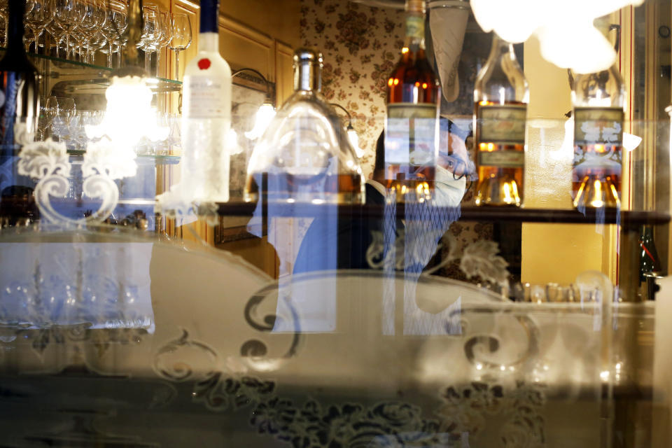 A waiter of Alain Ducasse's restaurant « Allard » is seen through a glass, in Paris, Thursday, June 11, 2020. French Michelin-starred chef Alain Ducasse unveils virus-protection measures as he prepares to reopen his restaurants, including a new filtration system that works to stop virus particles from the air traveling to neighboring tables. (AP Photo/Thibault Camus)