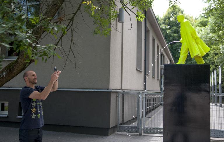 A man takes a photo of the fountain of "Pissing Lenin" created by a pair of Polish artists Malgorzata Szydlowska and Bartosz Szydlowski on June 24, 2014 in Nowa Huta