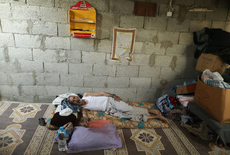 A Palestinian man uses a plastic tray to cool himself from the heat during power cut in his house in Khan Younis, in the southern Gaza Strip, July 3, 2017. REUTERS/Mohammed Salem