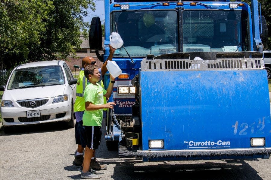 Republic Services driver Pete Torrez helps as Nathaniel Lopez brings out some extra recycling materials during July 2015 on the first day of operation for San Angelo's new trash collection system.