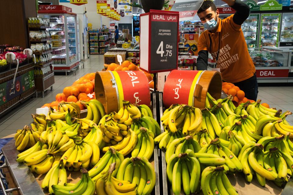 In this April 19, 2020 photo, a worker organizes bananas at a Carrefour supermarket while wearing a face mask amid the coronavirus pandemic, in Dubai, United Arab Emirates. The coronavirus pandemic has exposed just how vital foreigners are to the Gulf Arab countries where they work as medics, drivers, grocers and cleaners. (AP Photo/Jon Gambrell)