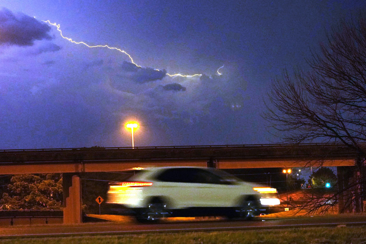 A vehicle races along a Jackson, Miss., street as lightning streaks across the sky, Tuesday evening, Nov. 29, 2022. (Rogelio V. Solis/AP)