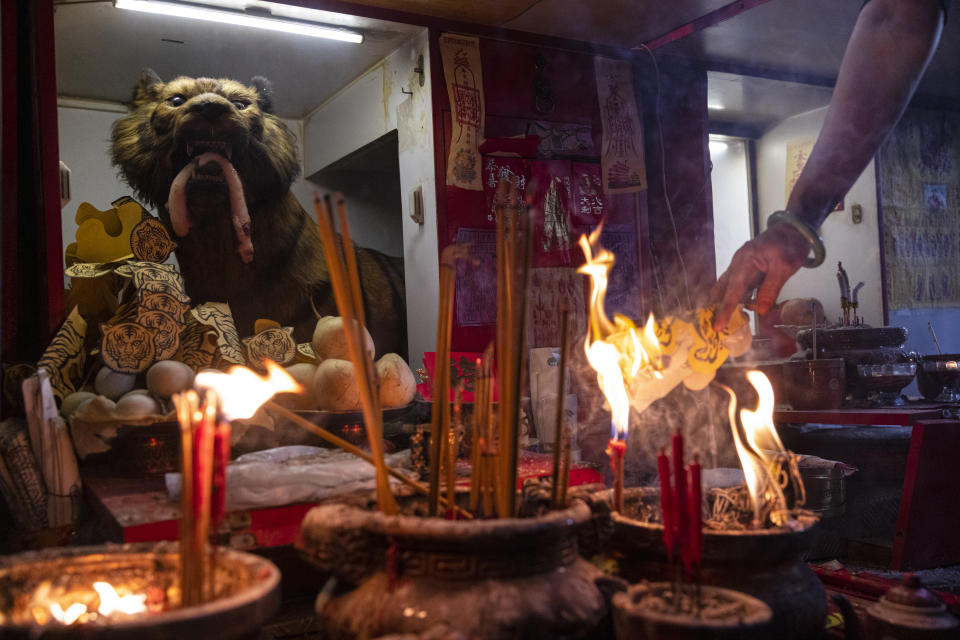 A practitioner burns a paper with the image of a tiger during a "villain hitting" ceremony on the day of "ging zat," as pronounced in Cantonese, which on the Chinese lunar calendar literally means "awakening of insects," under the Canal Road Flyover in Hong Kong on Monday, March 6, 2023. (AP Photo/Louise Delmotte)