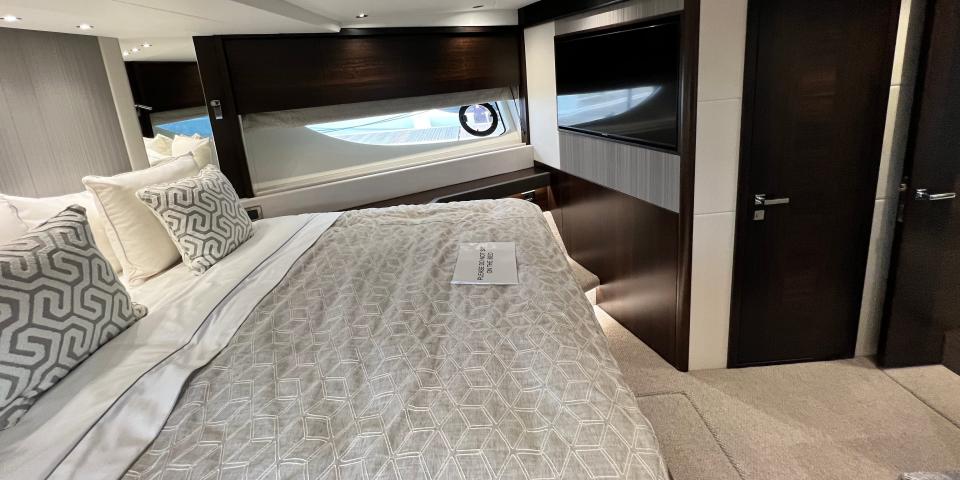An alternate view of the Sunseeker 76 Yacht's VIP cabin, featuring a TV in the background and a small door leading to a bathroom.