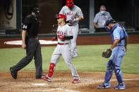 Los Angeles Angels' Tommy La Stella, center, steps on home plate after hitting a two run home run as Texas Rangers catcher Jeff Mathis, right, and umpire Mark Wegner, left, look on during the fifth inning of a baseball game in Arlington, Texas, Sunday, Aug. 9, 2020. (AP Photo/Ray Carlin)