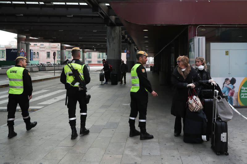 Members of the Military Emergency Unit (UME) talk with women at Atocha train station during partial lockdown as part of a 15-day state of emergency to combat the coronavirus (COVID-19) spread in Madrid