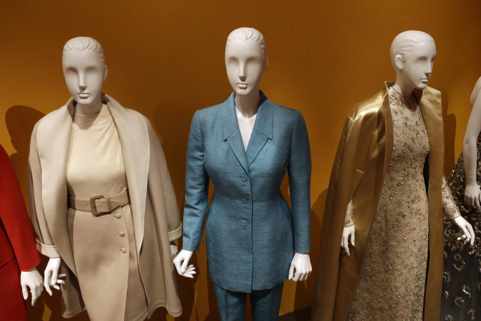 An Oscar de la Renta pantsuit, center, worn by Former first lady Hillary Rodham Clinton, is displayed next to other creations by the designer at the Clinton Presidential Library in Little Rock, Ark., Monday, July 8, 2013. The "Oscar de la Renta: American Icon" exhibit is on display at the Clinton library until Dec. 1. (AP Photo/Danny Johnston)