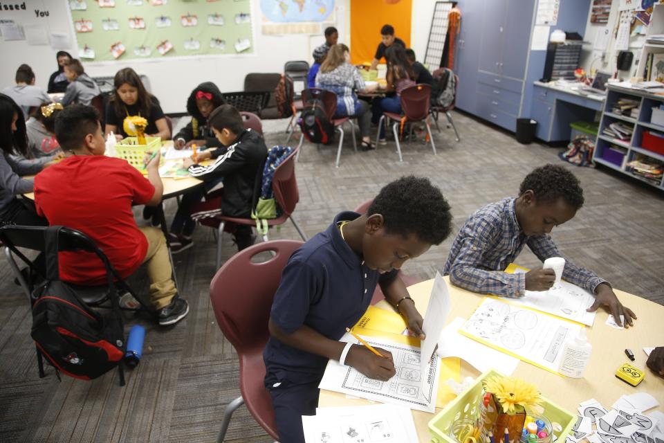 Boya Swedi, left, and Ibrahim Ahmed, right, work on their assignments at Valencia Newcomer School during class Thursday, Oct. 17, 2019, in Phoenix. Children from around the world are learning the English skills and American classroom customs they need to succeed at so-called newcomer schools. Valencia Newcomer School in Phoenix is among a handful of such public schools in the United States dedicated exclusively to helping some of the thousands of children who arrive in the country annually. (AP Photo/Ross D. Franklin)