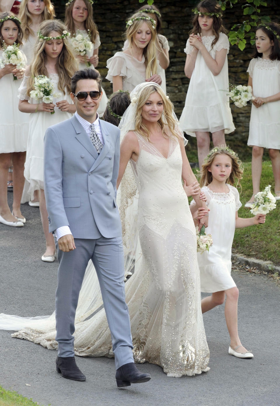 FILE - In this July 1, 2011 file photo, British model Kate Moss and British guitarist Jamie Hince pose for photographers with unidentified bridesmaids, after their wedding in the village of Southrop, England. Brides may want to take a page from the playbook of the supermodel Moss, who asked her friend John Galliano to make her a vintage style wedding dress, and the designer used Zelda Fitzgerald as inspiration. The cream-colored, bias cut gown featured an Art Deco motif along the bottom, and was embroidered with gold, spangled with gold paillettes. (AP Photo/Jonathan Short, file)