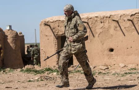 A foreign fighter that joined the Kurdish People's Protection Units (YPG), whom a YPG commander in the area says is British, carries his weapon as he walks near the frontline against Islamic State fighters, in the western countryside of Ras al-Ain March 10, 2015. REUTERS/Rodi Said