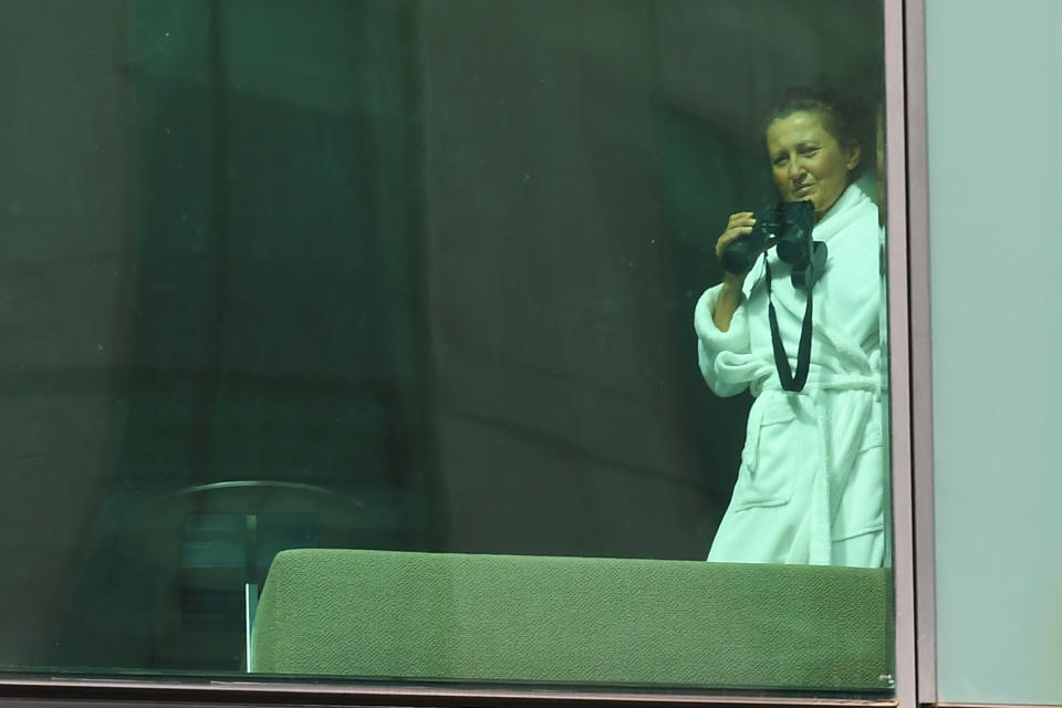 A lady is seen with binoculars in a hotel room at Crown Promenade where she is in mandatory quarantine after returning from overseas. Source: AAP