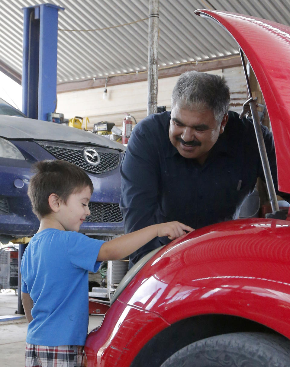 Rubén Moyoroqui habla con su hijo Rafael en su taller de reparaciones de automóviles en Tucson, Arizona, el 4 de septiembre del 2018. Moyoroqui entró legalmente a Estados Unidos en el 2001 desde México, pero se quedó tras vencerse su visa. Tiene cuatro hijos estadounidenses. Fue reportado a las autoridades de inmigración tras ser parado mientras recogía con su vehículo piezas de automóviles. (AP Foto/Rick Scuteri)