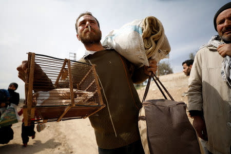 A man carries his belongings in the village of Beit Sawa, eastern Ghouta, Syria March 15, 2018. REUTERS/Omar Sanadiki