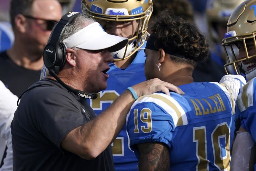 UCLA head coach Chip Kelly, left, congratulates running back Kazmeir Allen.